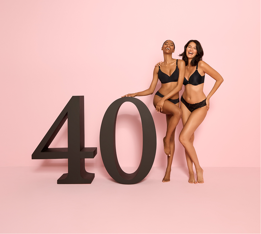 Deux mannequins vêtus de soutiens-gorge et culottes noirs posant à côté d’un panneau “40” pour célébrer le 40e anniversaire de la la Vie en Rose